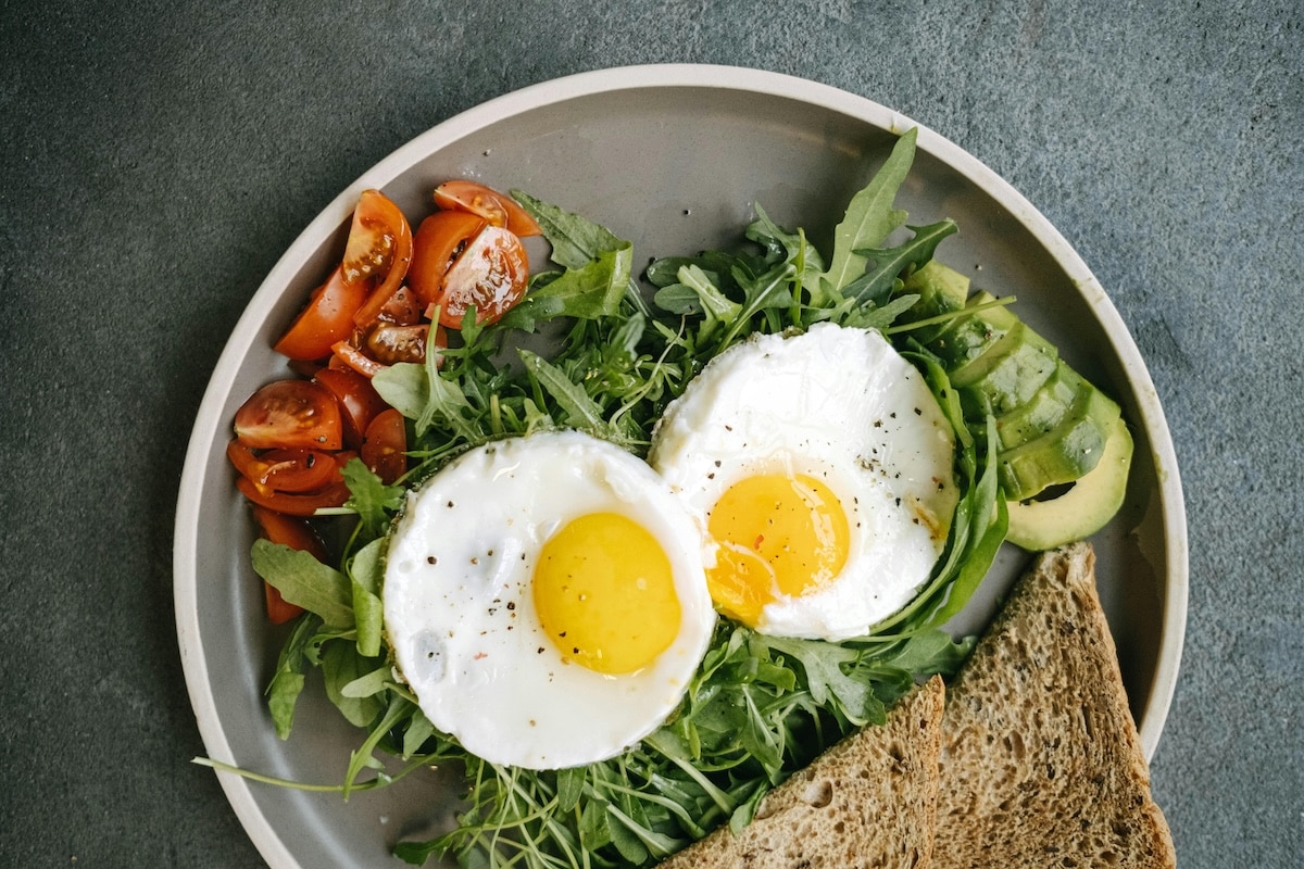 Balanced PCOS-friendly breakfast with eggs, leafy greens, avocado, and whole grain toast to support hormone balance and clear skin