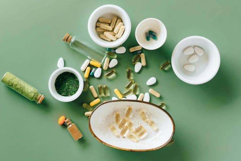 PCOS supplements scattered on a green background representing key vitamins and nutrients used for hormonal and metabolic support in PCOS.