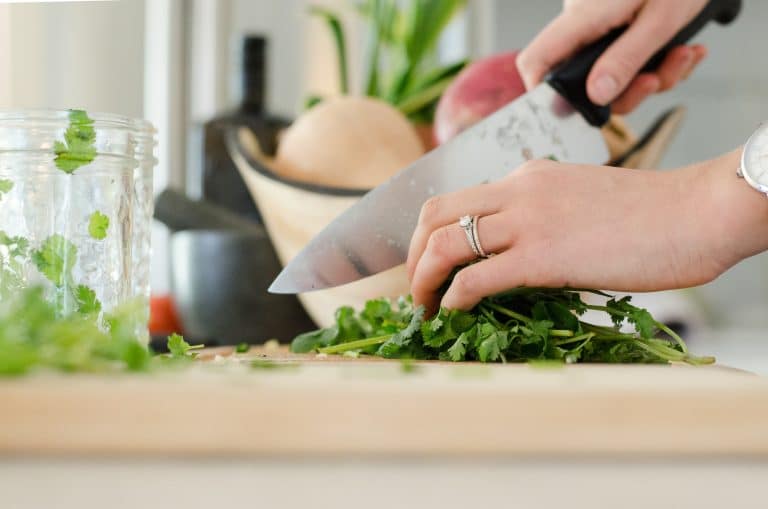 Woman chopping fresh greens on a wooden board — preparing a healthy salad to support gut health and PCOS nutrition.