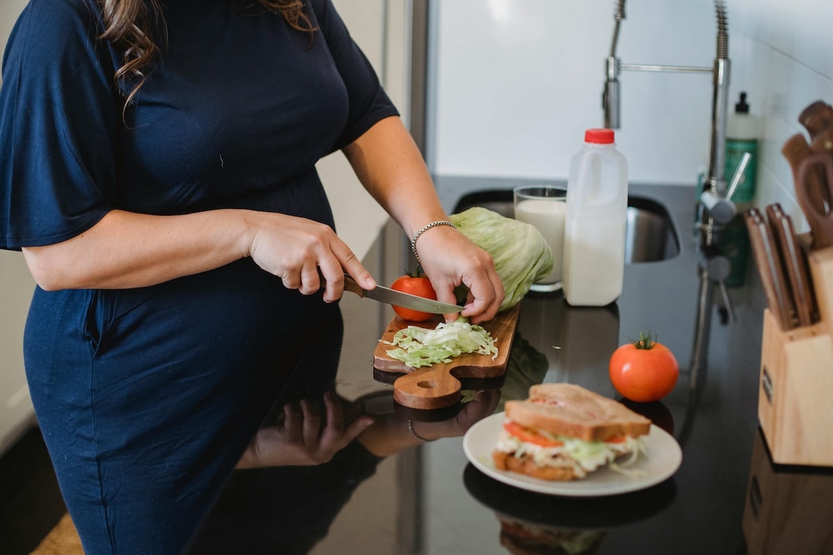 Women preparing a sandwich at a kitchen counter, emphasizing how gluten can be used in a balanced diet for PCOS management.