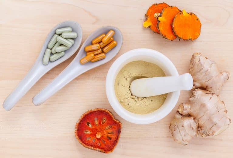 Berberine capsules, turmeric root, and powdered supplements arranged on a neutral background, representing supplements often discussed in PCOS care