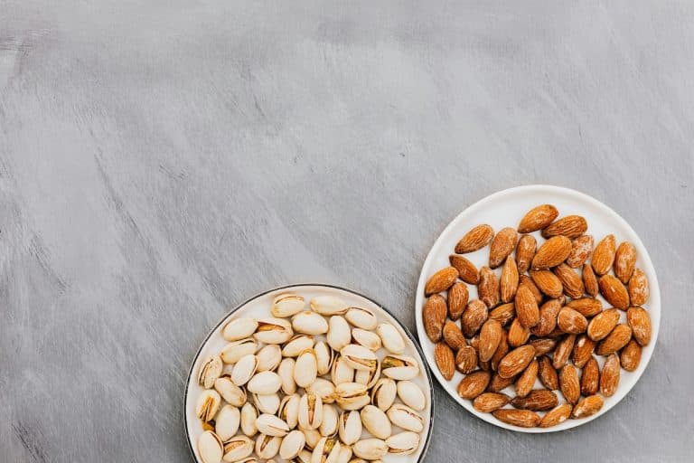 Two bowls, one filled with almond and the other filled with pistachios