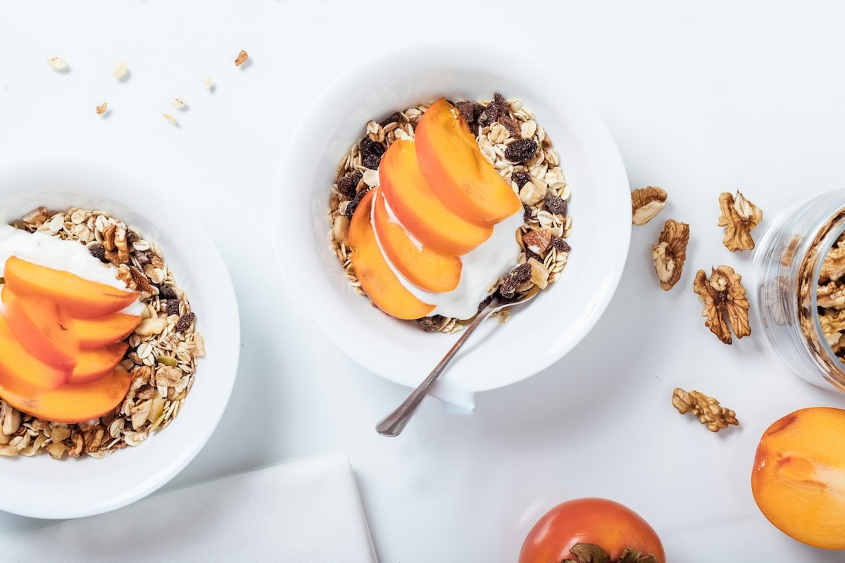 Bowls filled with creamy Greek yogurt, fresh peach slices, and crunchy granola as a Bedtime Snack idea for Gestational Diabetes