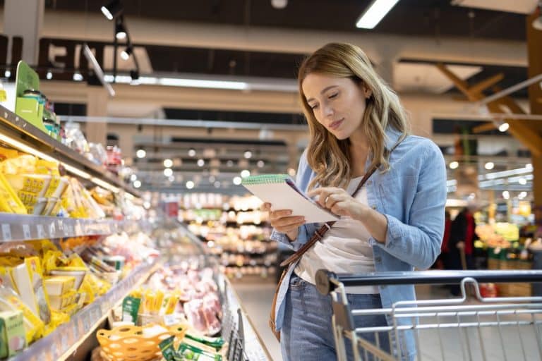 Woman shopping for healthy foods with a PCOS grocery list in hand, selecting fresh produce and whole foods for hormone balance.