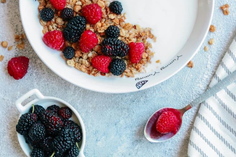 A bowl of high-fiber granola topped with blackberries and raspberries on yogurt, part of a high-fiber meal plan for PCOS and blood sugar balance.