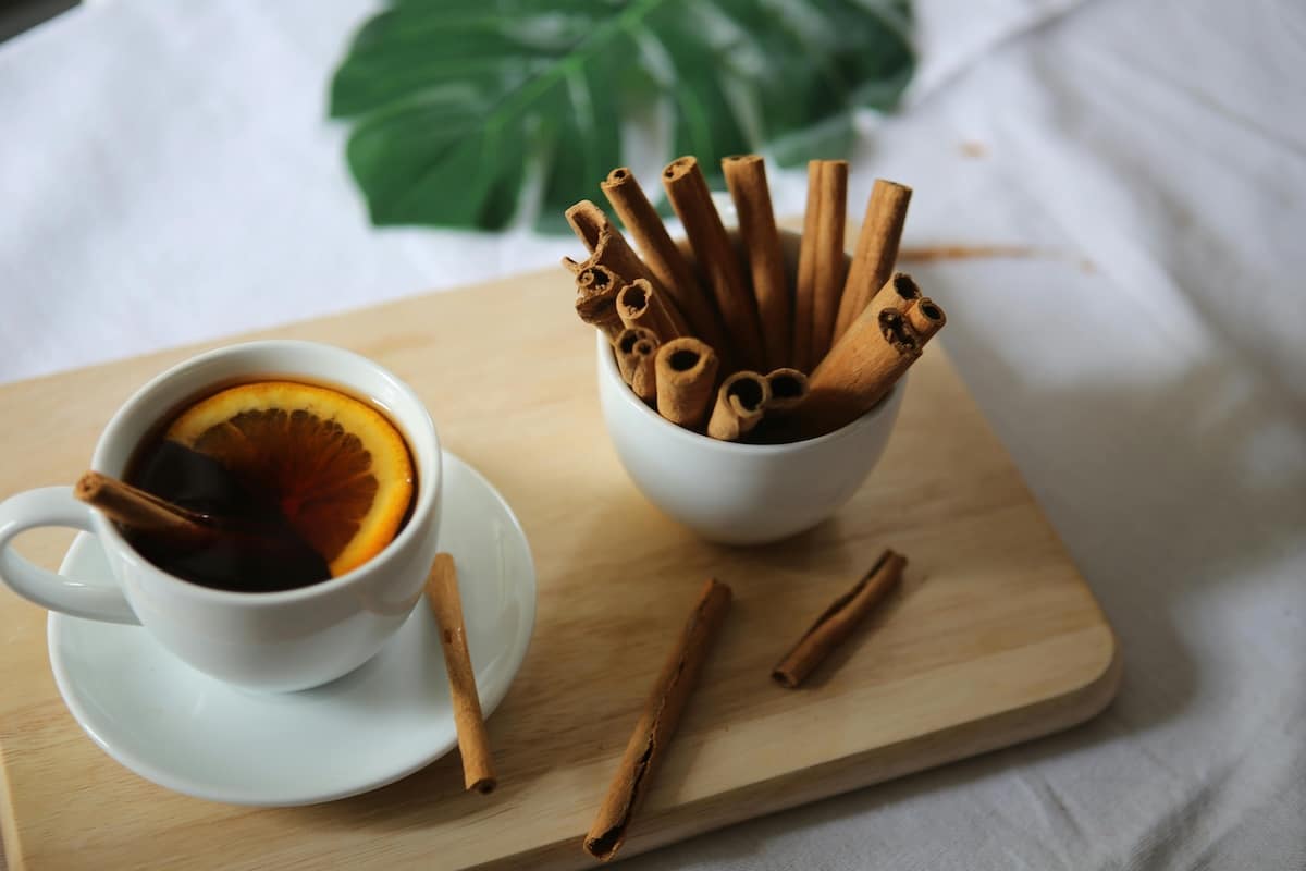 A warm cup of cinnamon tea surrounded by cinnamon sticks—one of the best teas for PCOS to support blood sugar balance and reduce inflammation.