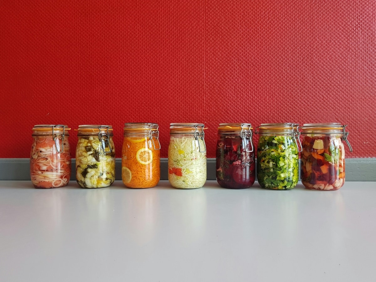Assorted jars of colourful fermented vegetables including sauerkraut, kimchi, and pickles — gut-friendly probiotic foods that support PCOS gut health.