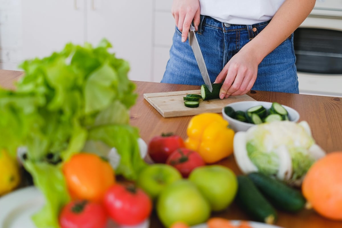 Photo of women chopping and preparing fresh vegetables on a kitchen counter, illustrating importance of vegetables to stay full, support blood sugar balance, and manage PCOS symptoms after stopping Ozempic.