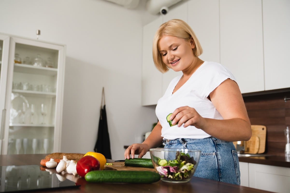 Woman preparing a healthy meal in a kitchen, illustrating the discussion around PCOS renamed PMOS and women’s metabolic health